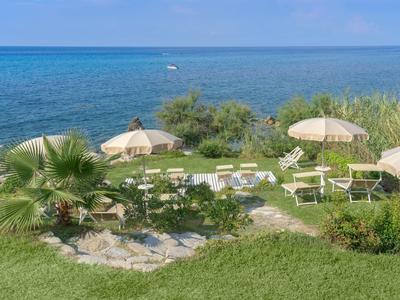 Widok na leżaki i parasole na wybrzeżu z morzem w tle.