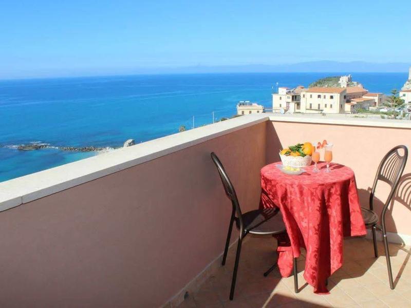 Balkon s malým stolem a dvěma židlemi s výhledem na moře a město