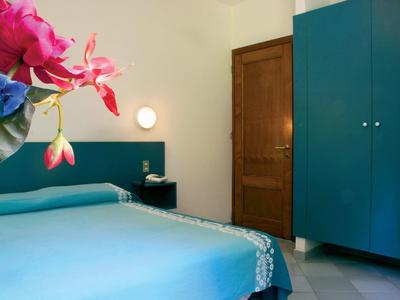 Schlafzimmer mit blauem Bett, blauem Schrank, Holztür und Blumen im Vordergrund.