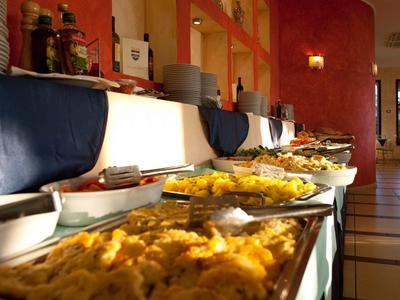 Buffet met verschillende warme gerechten in een restaurant met een rode muur.