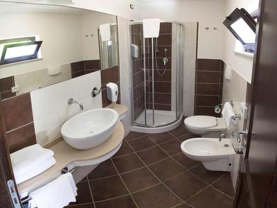 Moderne badkamer met douche, wastafel, toilet en bidet in warme bruintinten.