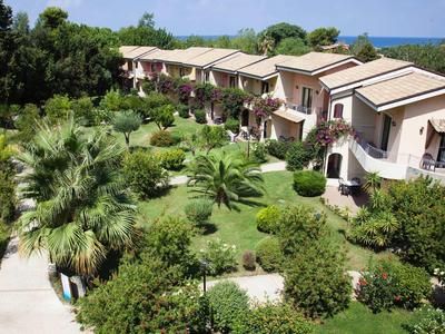 Rijhuizen met balkons in een weelderige groene tuin vlak bij de zee.