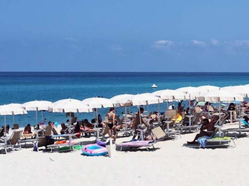 Breid zandstrand met veel parasols en ligstoelen aan zee