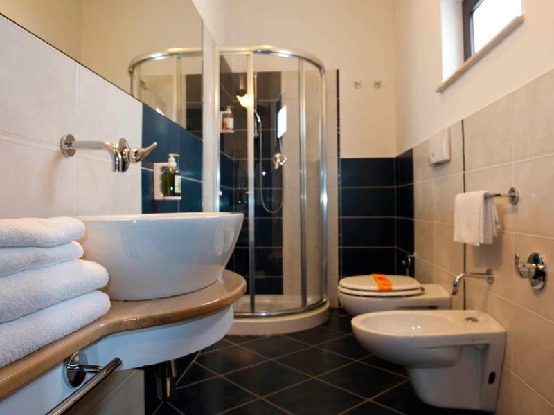Moderne badkamer met ronde glazen douche, wastafel, bidet en handdoeken.