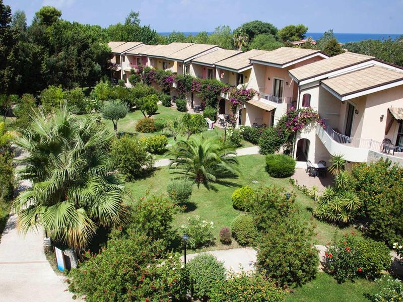 Rijhuizen met balkons in een weelderige groene tuin vlak bij de zee.