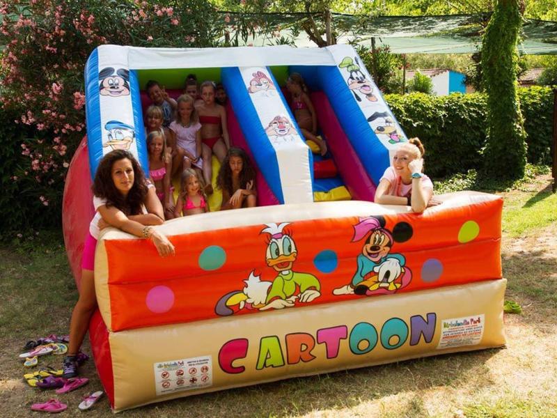 Opblaasbaar cartoon waterpark met kinderen en volwassenen op een zonnige dag buiten.