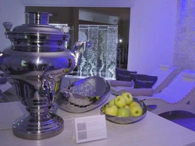 Moderní společenská místnost s samovarem, jablky a posezením při měkkém osvětlení.