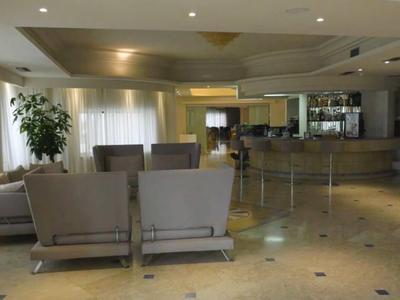 Helles, modernes Wartezimmer mit grauen Sesseln, großen Fenstern und Pflanzen in neutralen Farben.