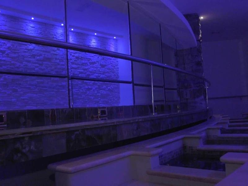 Moderní spa s modrým LED osvětlením a lehátky.