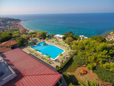 Blick auf einen Pool und einen gepflegten Garten mit Blick auf das Meer an der Küste.