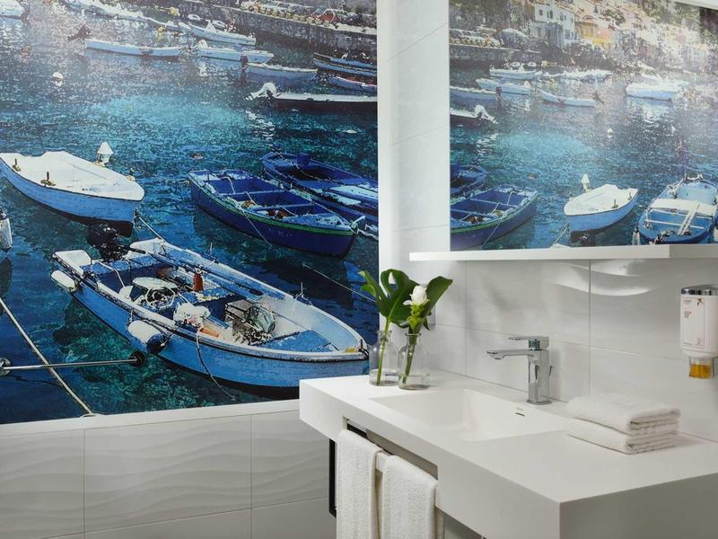 Bagno moderno con lavabo, asciugamani e quadro marino sulla parete.