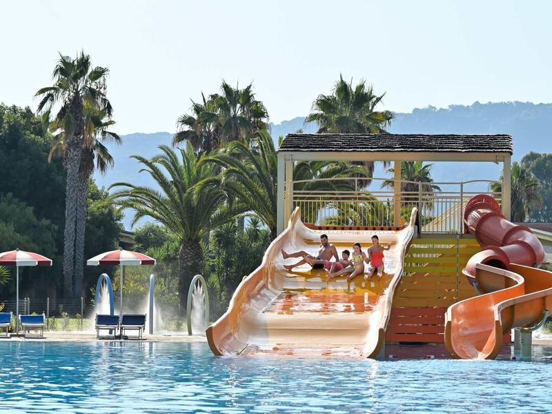 Scivoli d'acqua e piscina con palme sullo sfondo in un resort per vacanze.