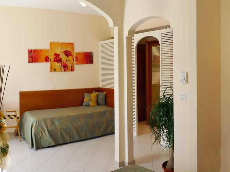 Heller Wohnraum mit Sofa, weißem Boden, braunen Wänden, Fernseher und geometrischem Wandbild.