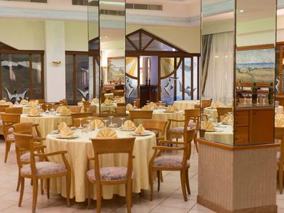 Salle à manger élégante avec tables rondes, couverts et chaises en bois dans un hôtel.