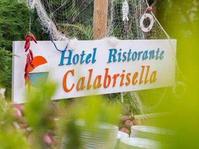Panneau avec l'inscription Hotel Ristorante Calabrisella parmi des feuilles vertes.