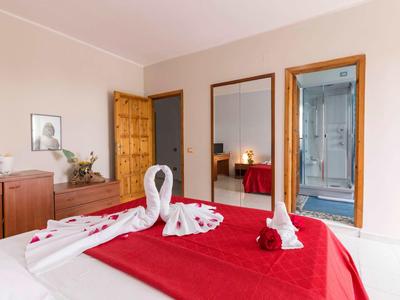 Chambre d'hôtel confortable avec couette rouge et serviettes pliées en forme de cygnes.