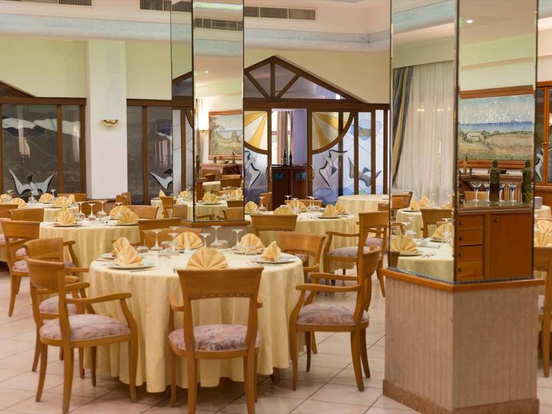Salle à manger élégante avec tables rondes, couverts et chaises en bois dans un hôtel.