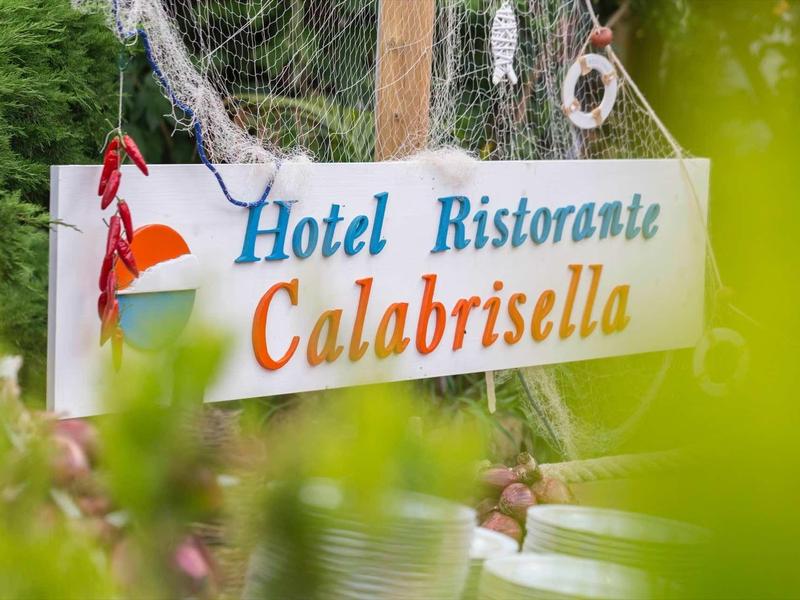 Panneau avec l'inscription Hotel Ristorante Calabrisella parmi des feuilles vertes.