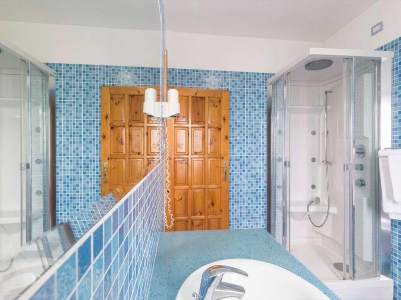 Salle de bain moderne avec carrelage bleu, deux douches et une baignoire.