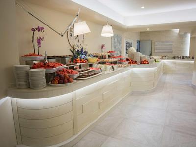 Hell beleuchtetes Buffet mit verschiedenen Speisen in einem modernen Hotelrestaurant.