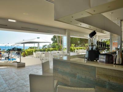 Bar moderne avec vue sur une piscine et la mer dans un cadre hôtelier.