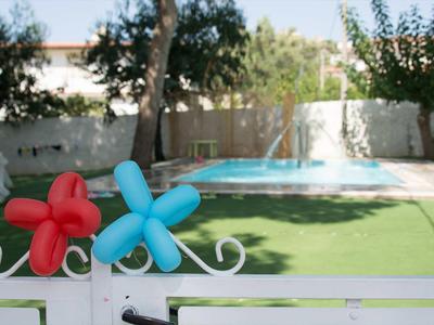Vue d'une piscine dans un jardin avec pelouse verte et fleurs décoratives colorées sur la clôture.