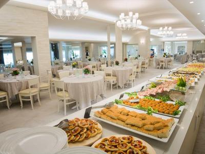 Une grande salle à manger avec de longues tables de buffet et des tables dressées dans un restaurant d'hôtel.
