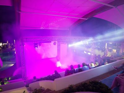 Bühne mit pinkem Licht und Publikum in einem überdachten Veranstaltungsort bei Nacht.