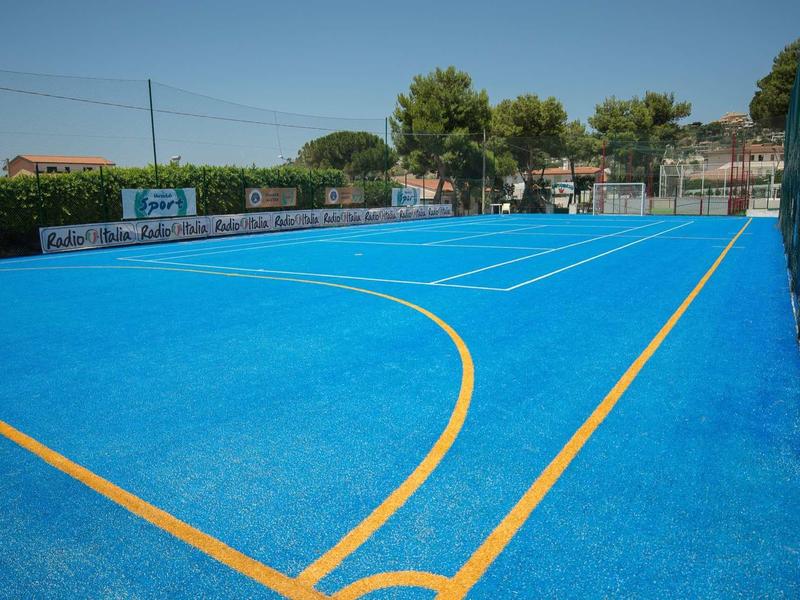 Terrain de tennis bleu avec lignes jaunes et vue sur des arbres et des bâtiments en arrière-plan