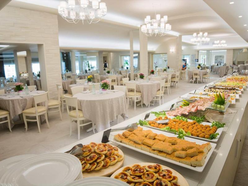 Une grande salle à manger avec de longues tables de buffet et des tables dressées dans un restaurant d'hôtel.