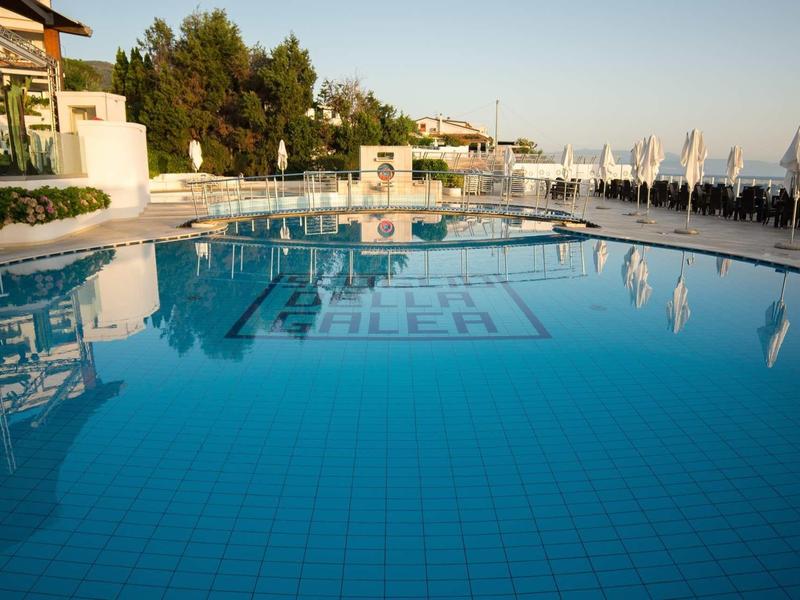 Piscine claire avec palmiers et chaises longues sur la plage au coucher du soleil.