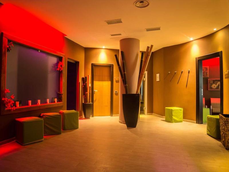 Intérieur d'hôtel moderne éclairé chaudement avec des sièges cubes et des miroirs aux murs.