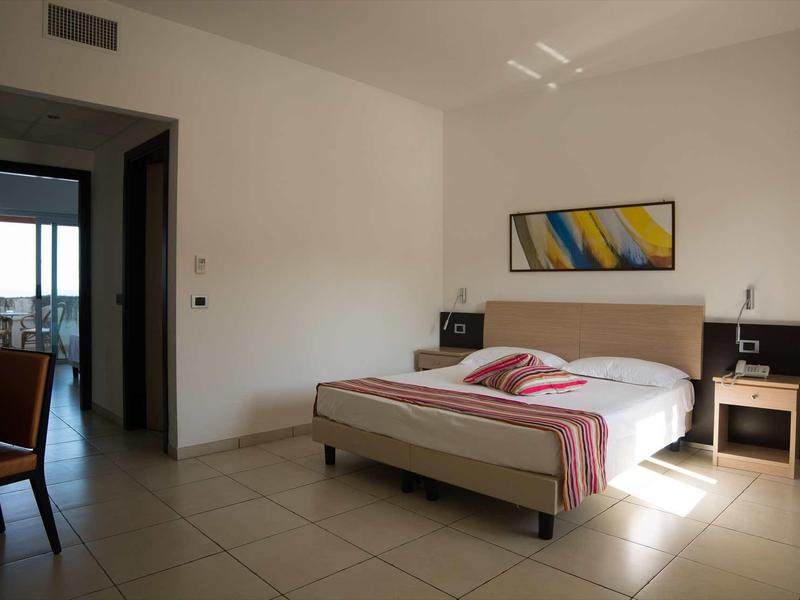 Chambre d'hôtel moderne avec lit double, tables de nuit et vue sur le balcon