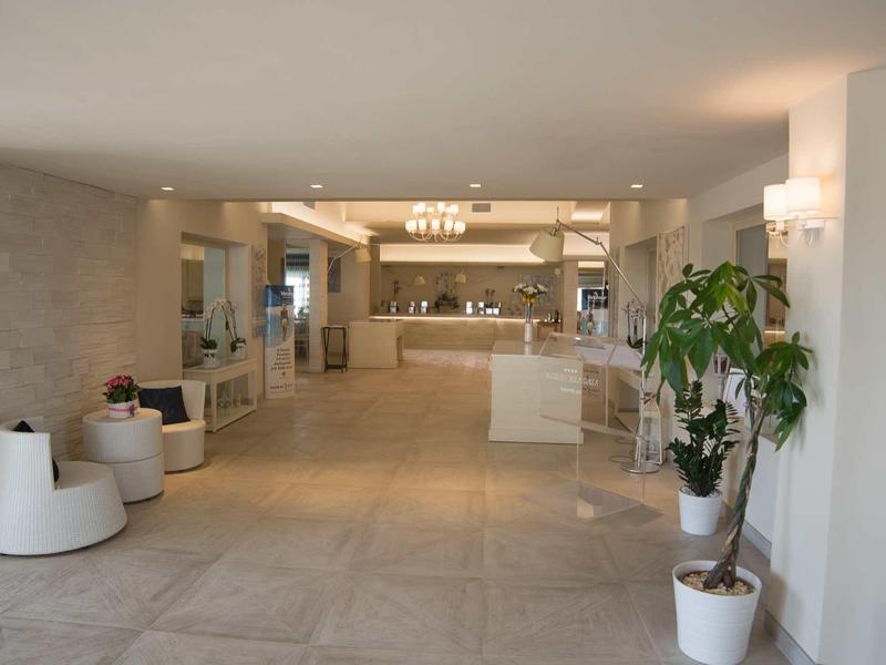 Hall d'hôtel lumineux et moderne avec sol en marbre, réception et plantes.
