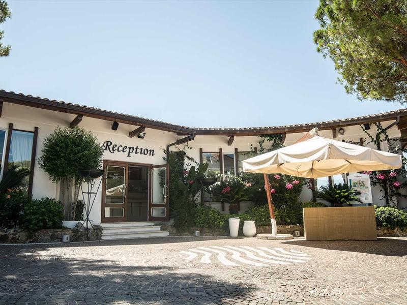 Vue extérieure d'une réception d'hôtel avec parasol et arbres.