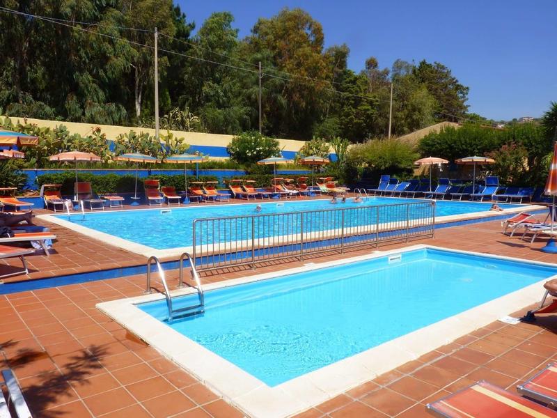 Zwei rechteckige Schwimmbecken mit blauen Liegestühlen und Sonnenschirmen auf rotem Fliesenboden.