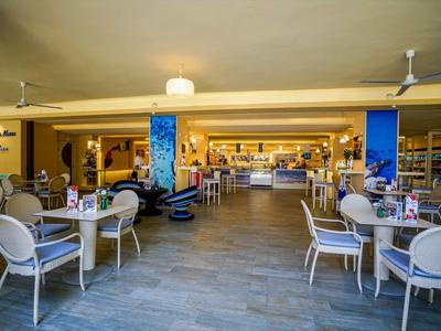 Offener, moderner Hotelrestaurantbereich mit Tischen und Stühlen, moderner Beleuchtung und Bar im Hintergrund.