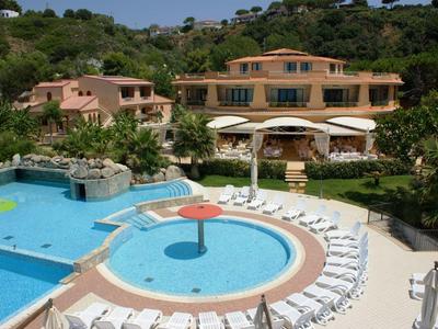 Outdoor pool area with circular kiddie pool, sun loungers, and Mediterranean-style hotel building in background.