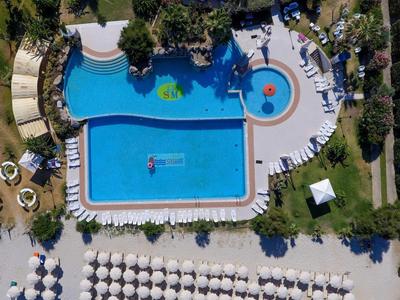 Aerial view of a hotel pool with umbrellas and sun loungers on the beach.