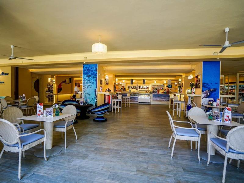 Modern open dining area with white chairs and light tables in a hotel.