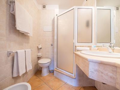 Salle de bain lumineuse avec douche, lavabo, toilette et serviettes sur les murs.