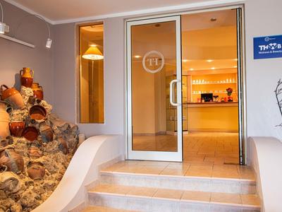 Entrée d'hôtel avec porte vitrée, amphores décoratives et marches