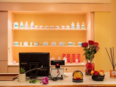 Bureau de réception avec ordinateur, produits cosmétiques et roses dans une pièce chaleureusement éclairée.