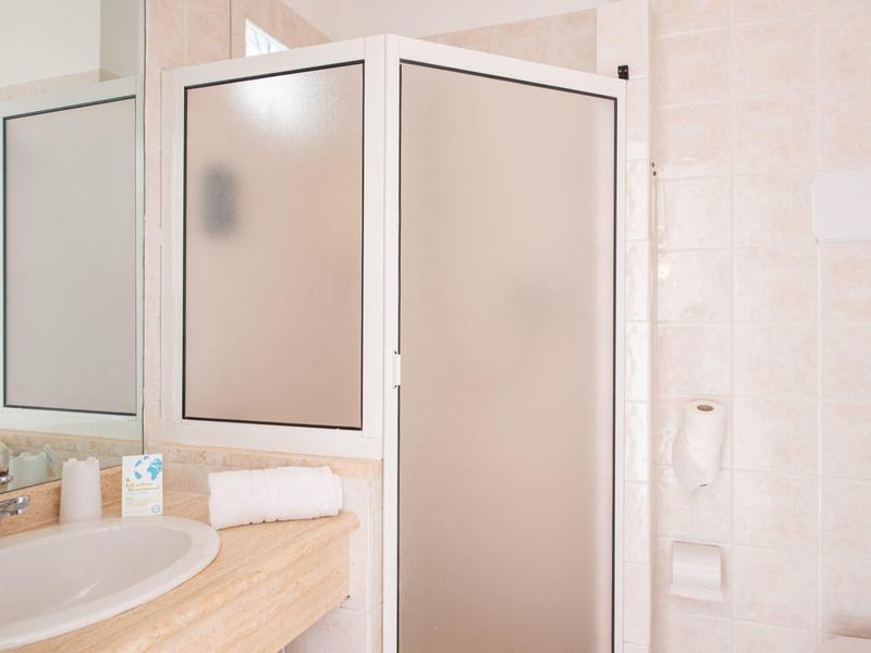 Coin de salle de bain compact avec lavabo, miroir et cabine de douche en verre dépoli.