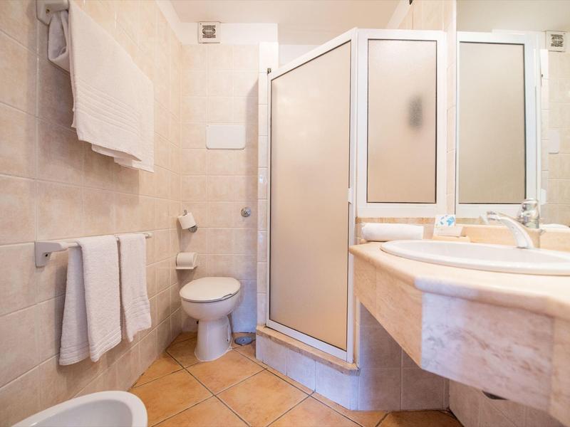 Salle de bain lumineuse avec douche, lavabo, toilette et serviettes sur les murs.