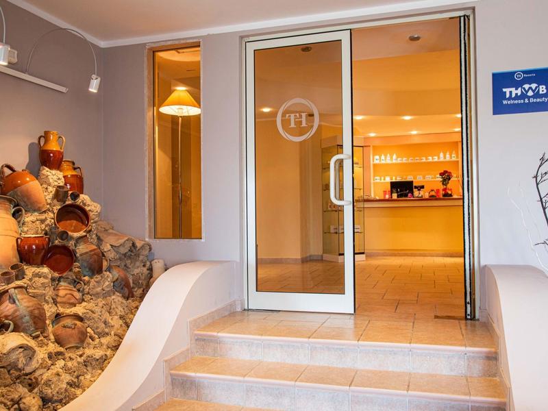 Entrée d'hôtel avec porte vitrée, amphores décoratives et marches