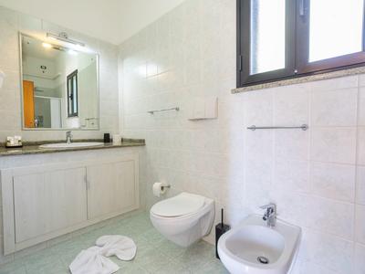 Salle de bain lumineuse avec lavabo, toilettes, bidet et serviettes au sol.