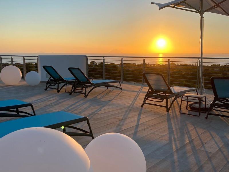 Terrasse avec chaises longues et vue sur le coucher de soleil au bord de la mer.