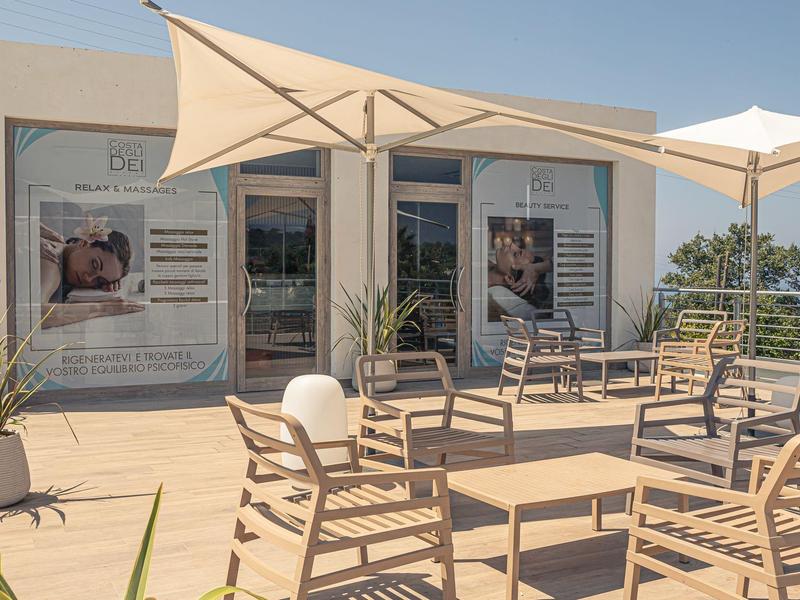Terrasse ensoleillée avec chaises et parasols devant un bâtiment moderne.