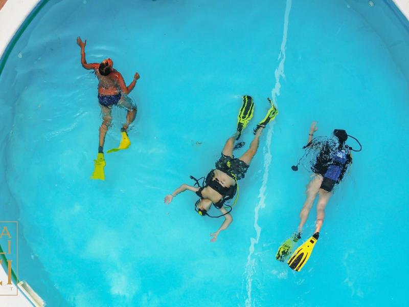 Trois personnes plongent dans une piscine ronde avec de l'eau bleue claire.